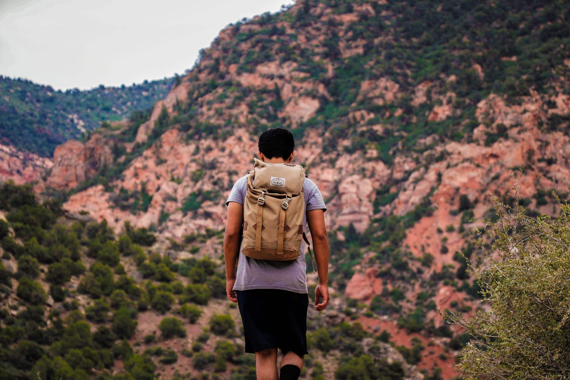 Hiker with a backpack walking along a red rock canyon trail near Orem, Utah