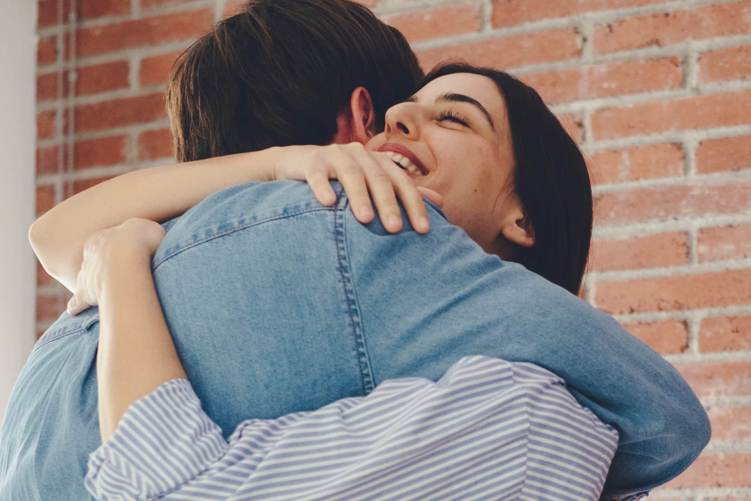Smiling couple hugging in front of a brick wall on a date in Orem, UT